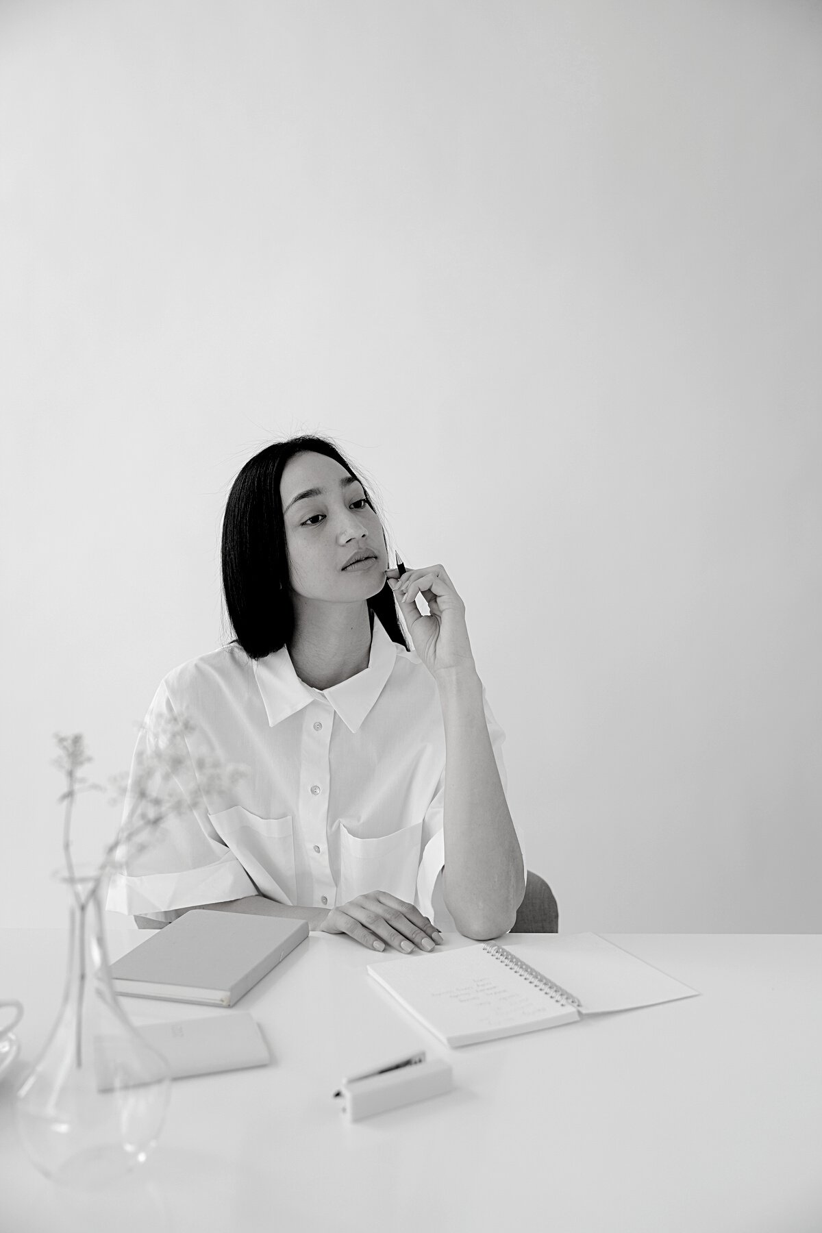 Thoughtful Asian employee with agendas at office table